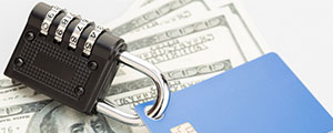 Pad lock hooked on a credit/debit card laying on top of cash