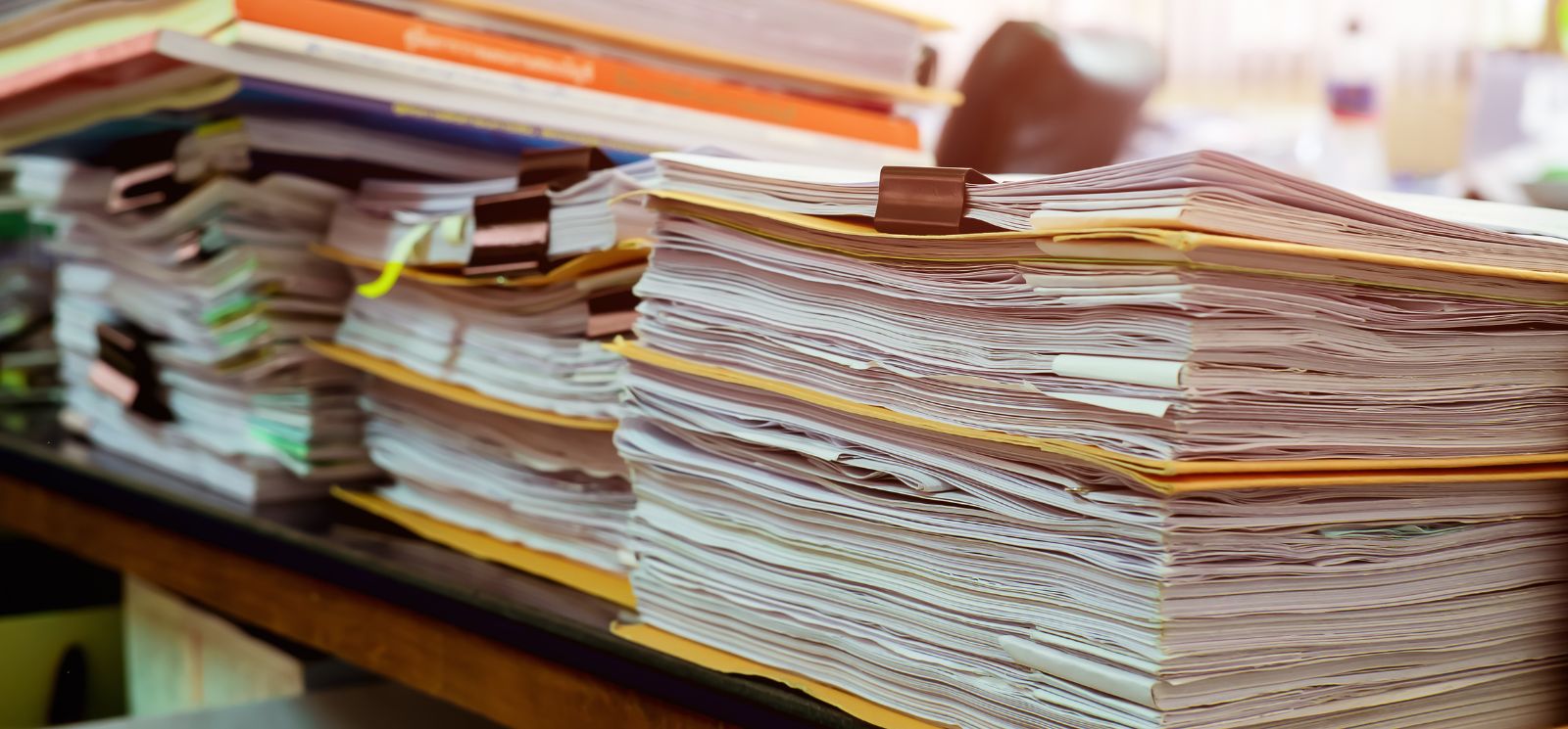 Stacks of papers with binder clips on desk